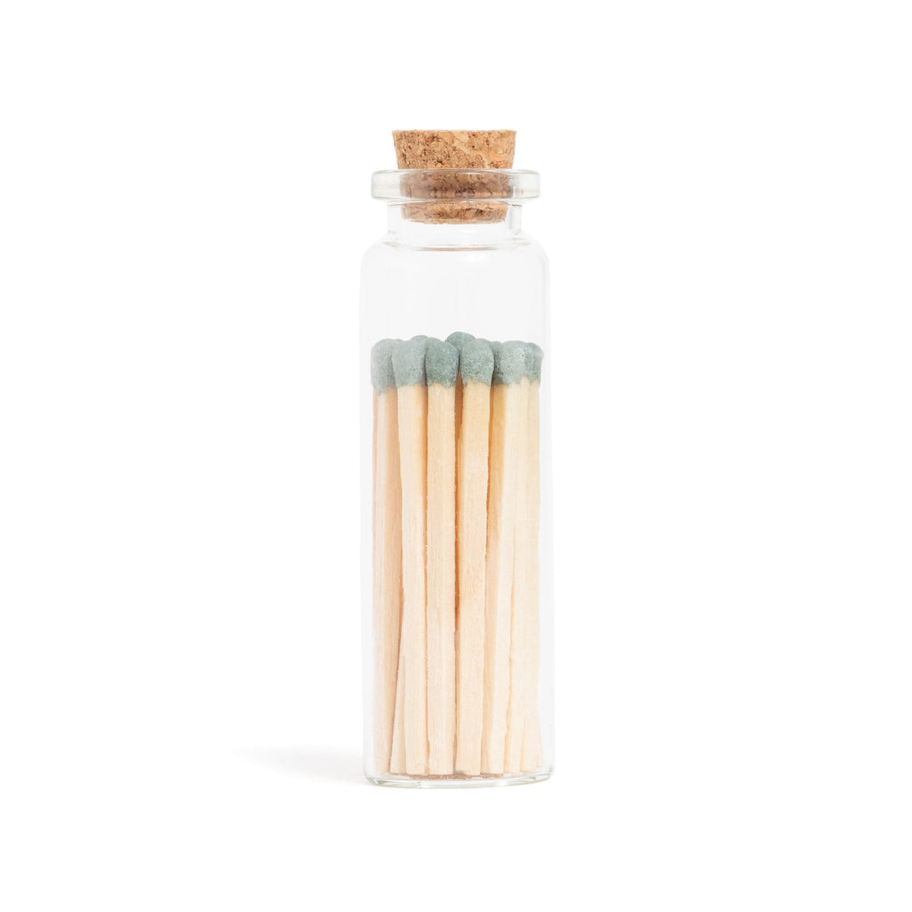sage green colored matchsticks in corked jar with match striker